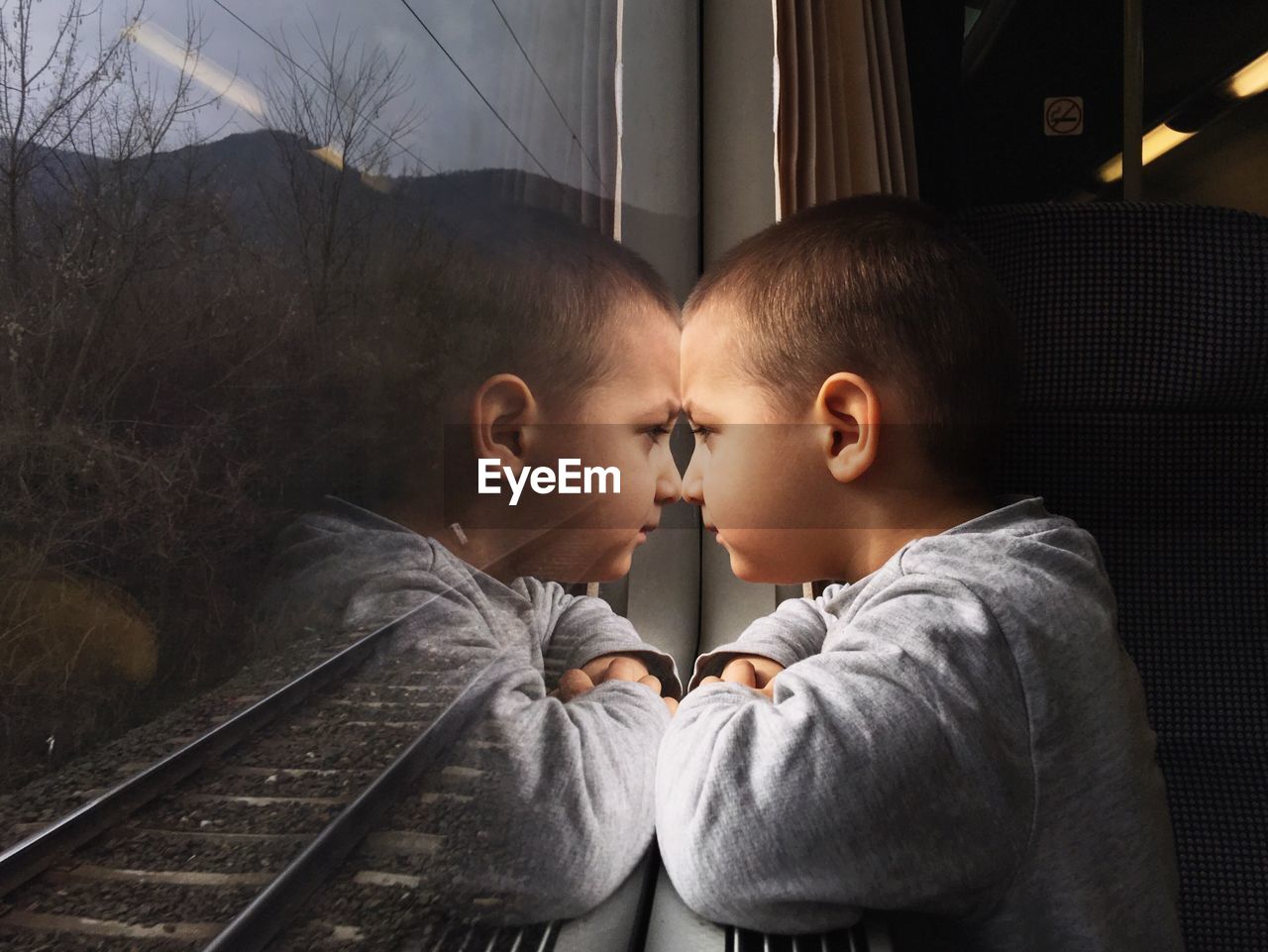Side view of boy looking through train window in journey