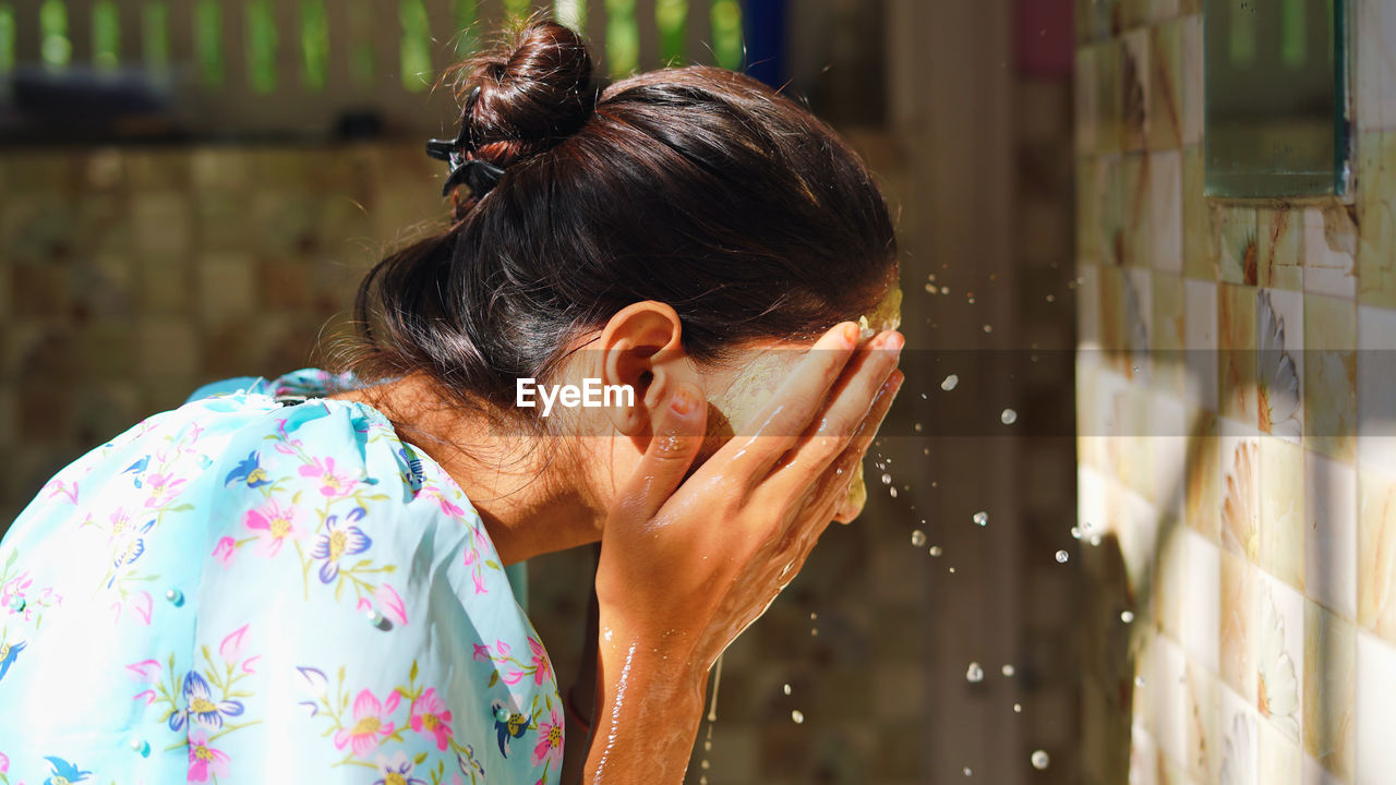 Beautiful woman is washing facial mask in bathroom after applying face mask.