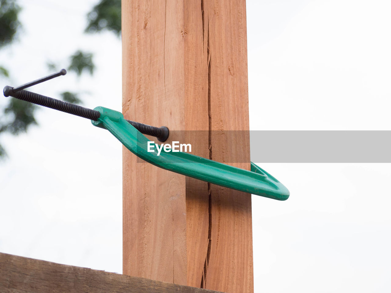 Close-up of c clamp on wood against sky