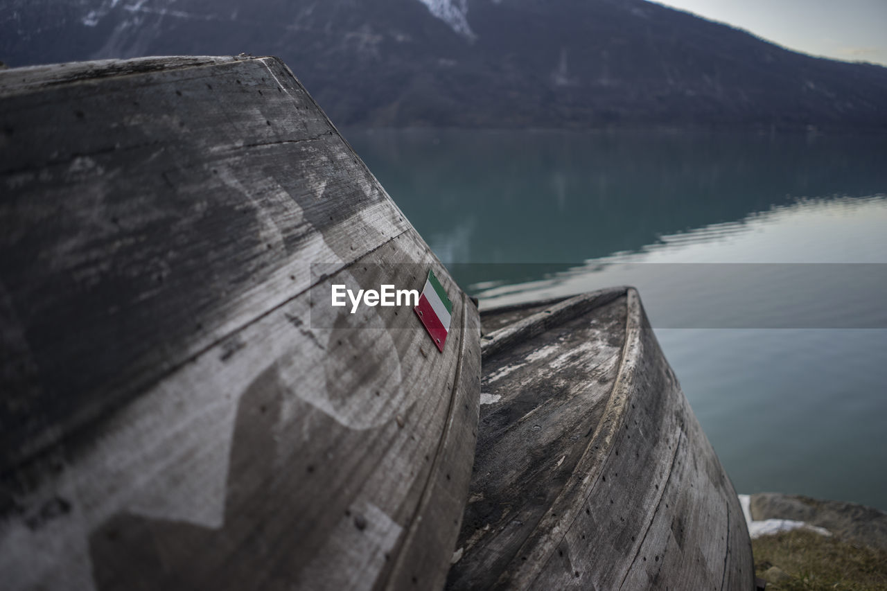 Wooden boats moored at riverbank against mountain