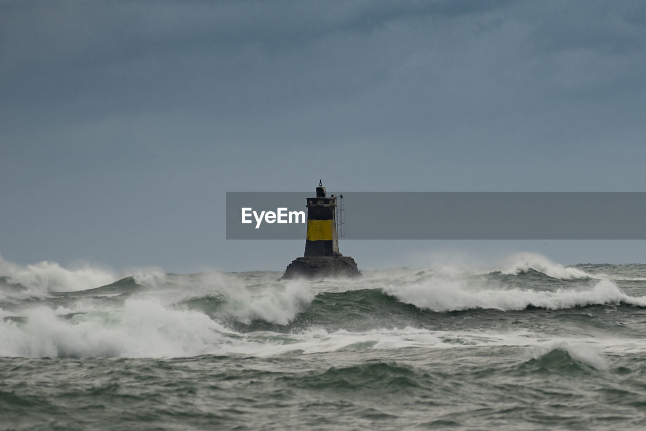 LIGHTHOUSE ON SHORE AGAINST SKY