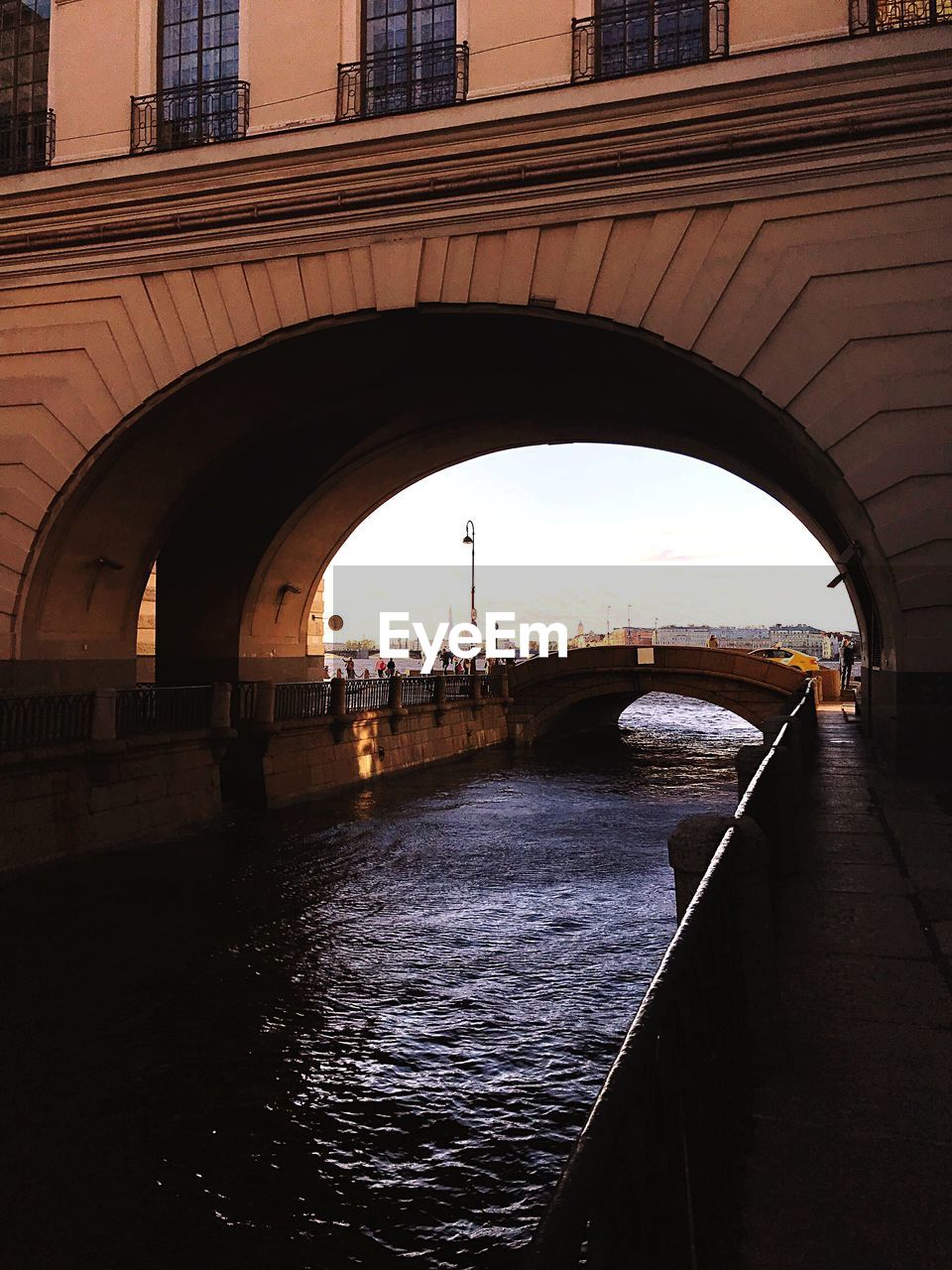 Arch bridge over river in city against sky