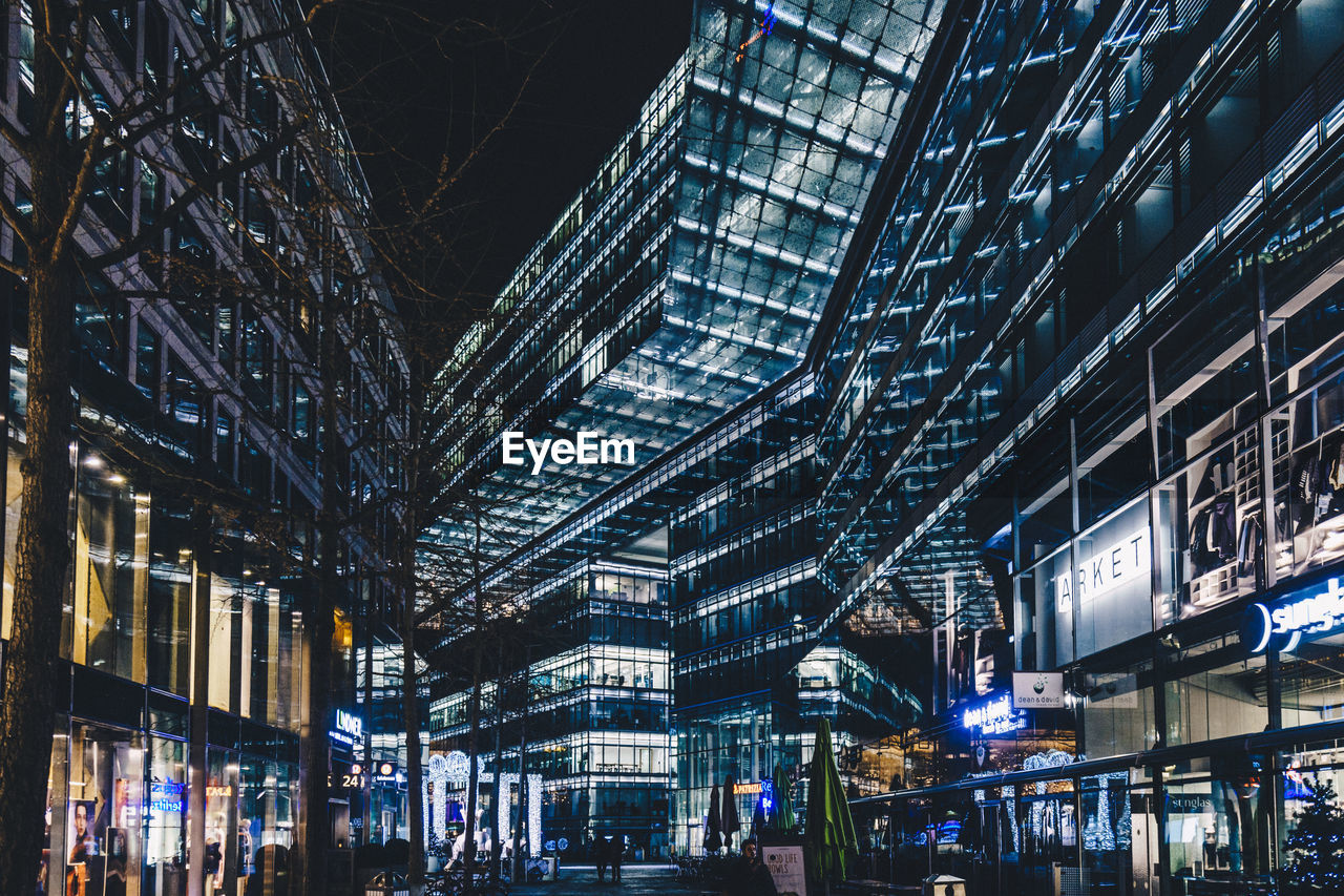 LOW ANGLE VIEW OF ILLUMINATED MODERN BUILDING AT NIGHT