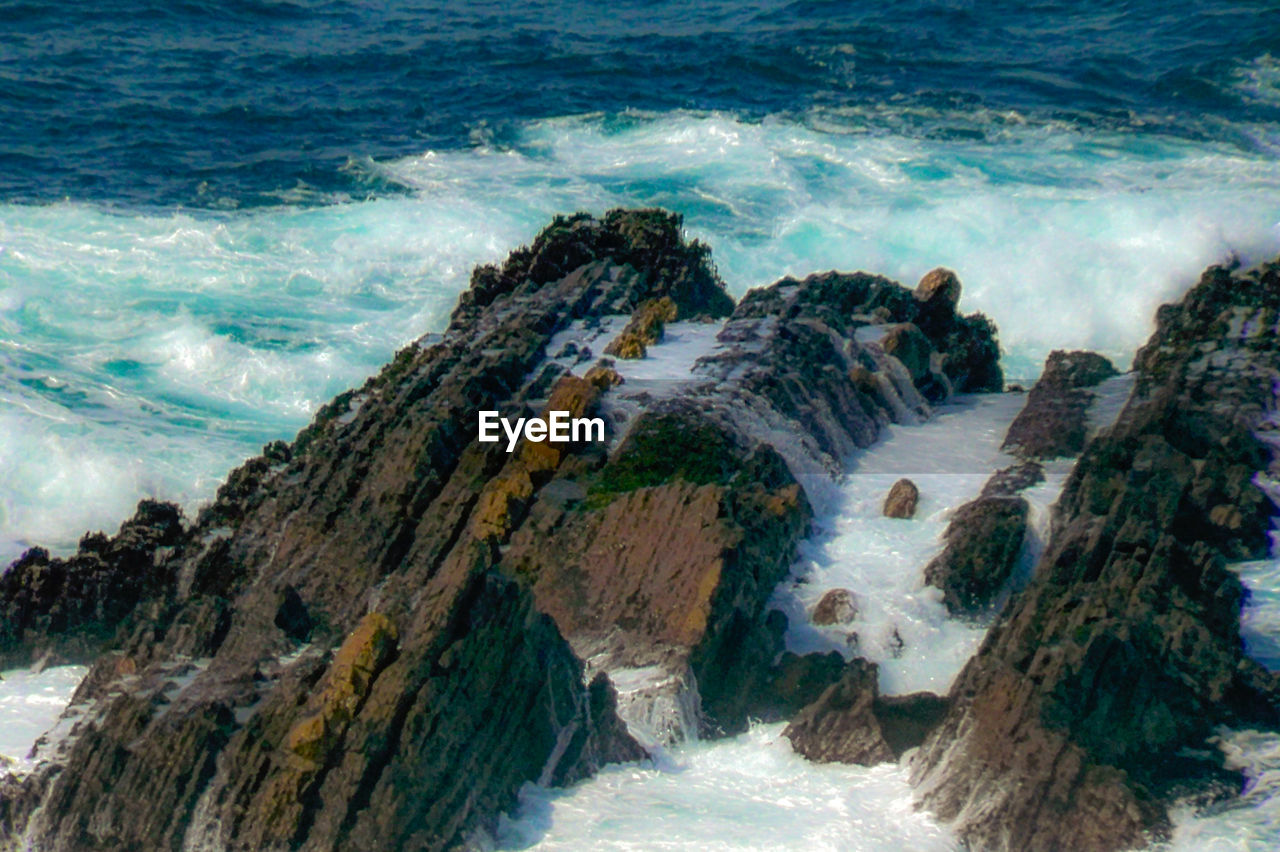 HIGH ANGLE VIEW OF ROCKS ON SHORE AT SEA