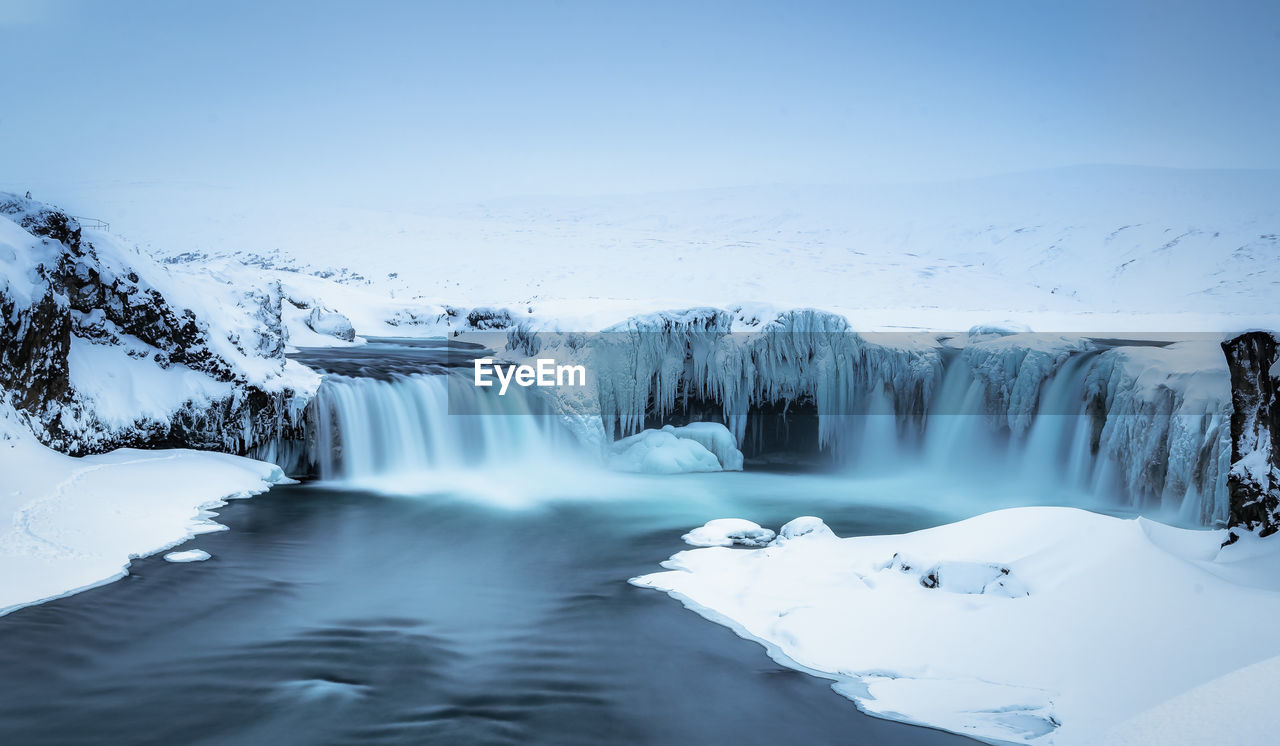 Scenic view of frozen river against sky during winter