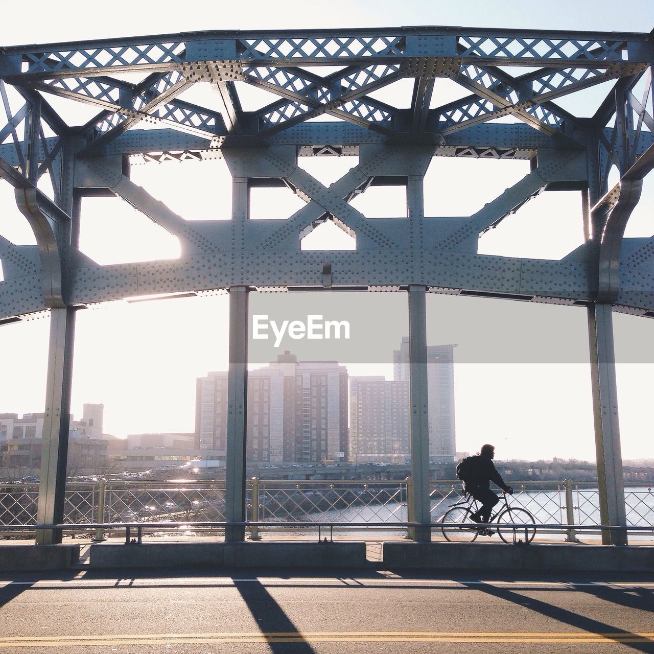 Man cycling on bridge against sky