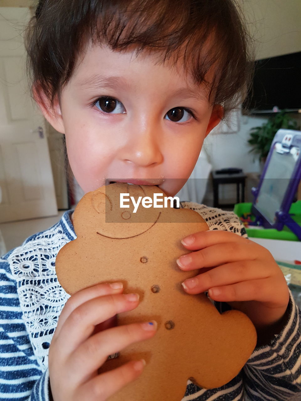 Portrait of cute girl eating gingerbread cookie at home