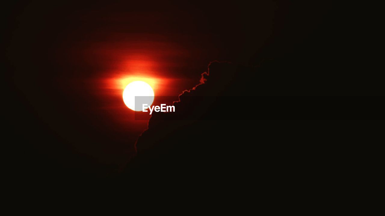 LOW ANGLE VIEW OF SUN SHINING THROUGH SILHOUETTE MOON