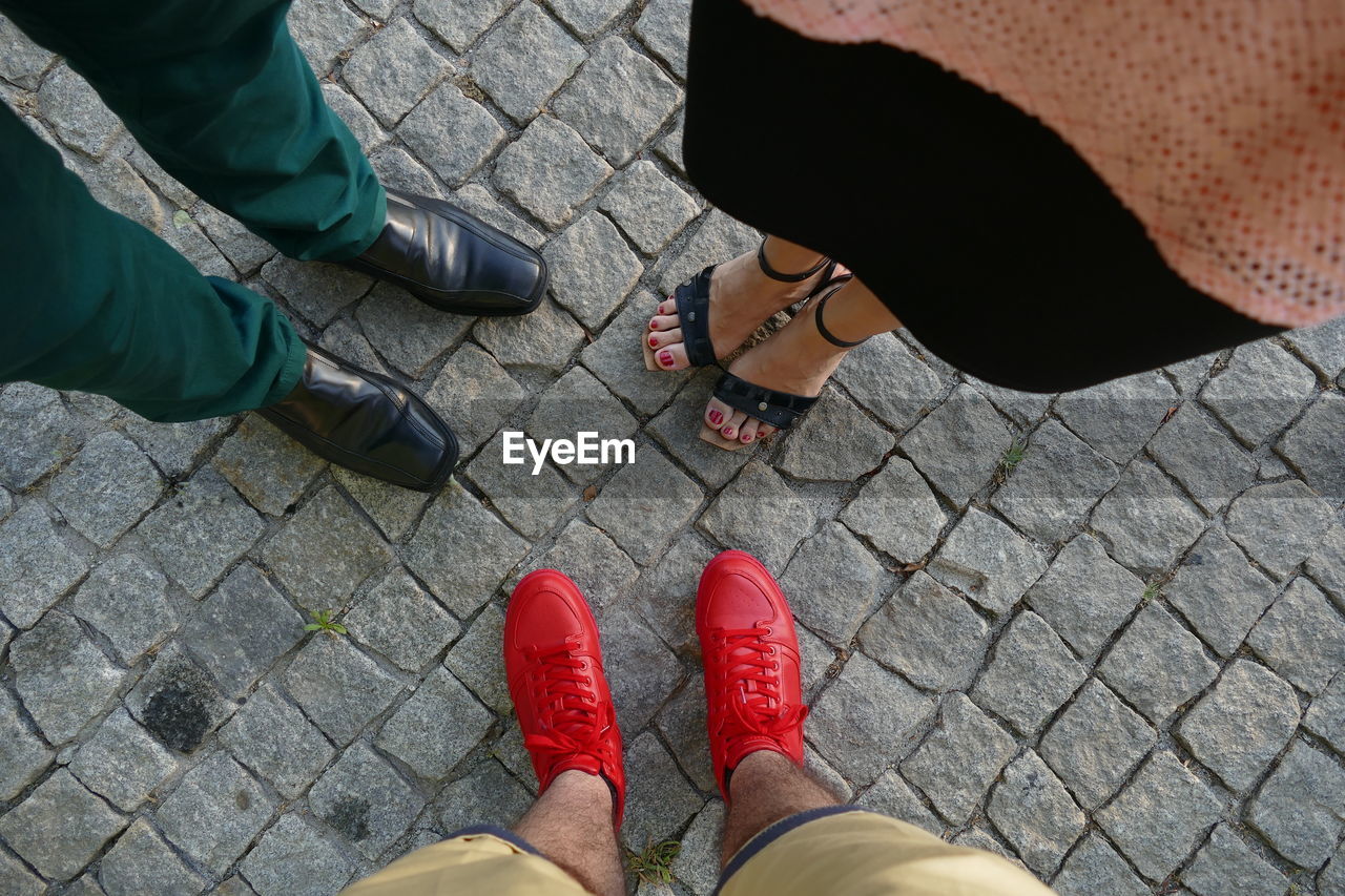 Low section of friends standing on cobblestone street