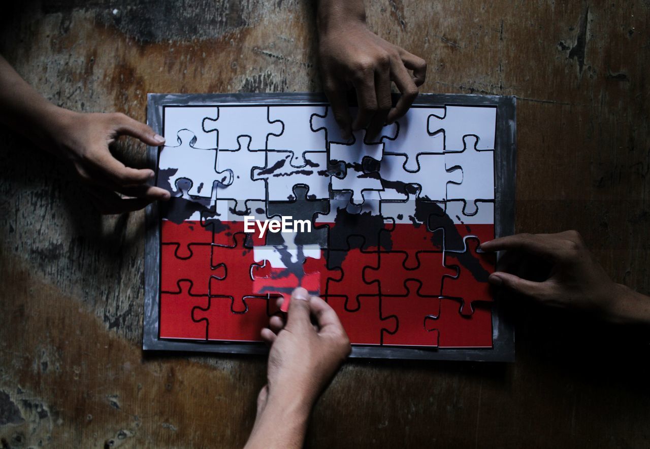 Cropped hands of people playing with jigsaw puzzle on table
