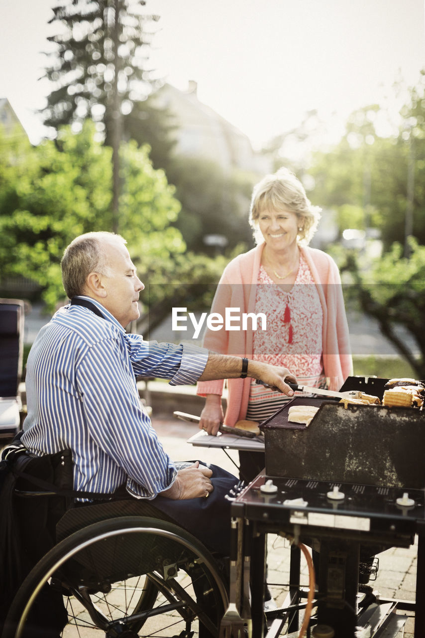 Happy mature couple barbecuing at yard