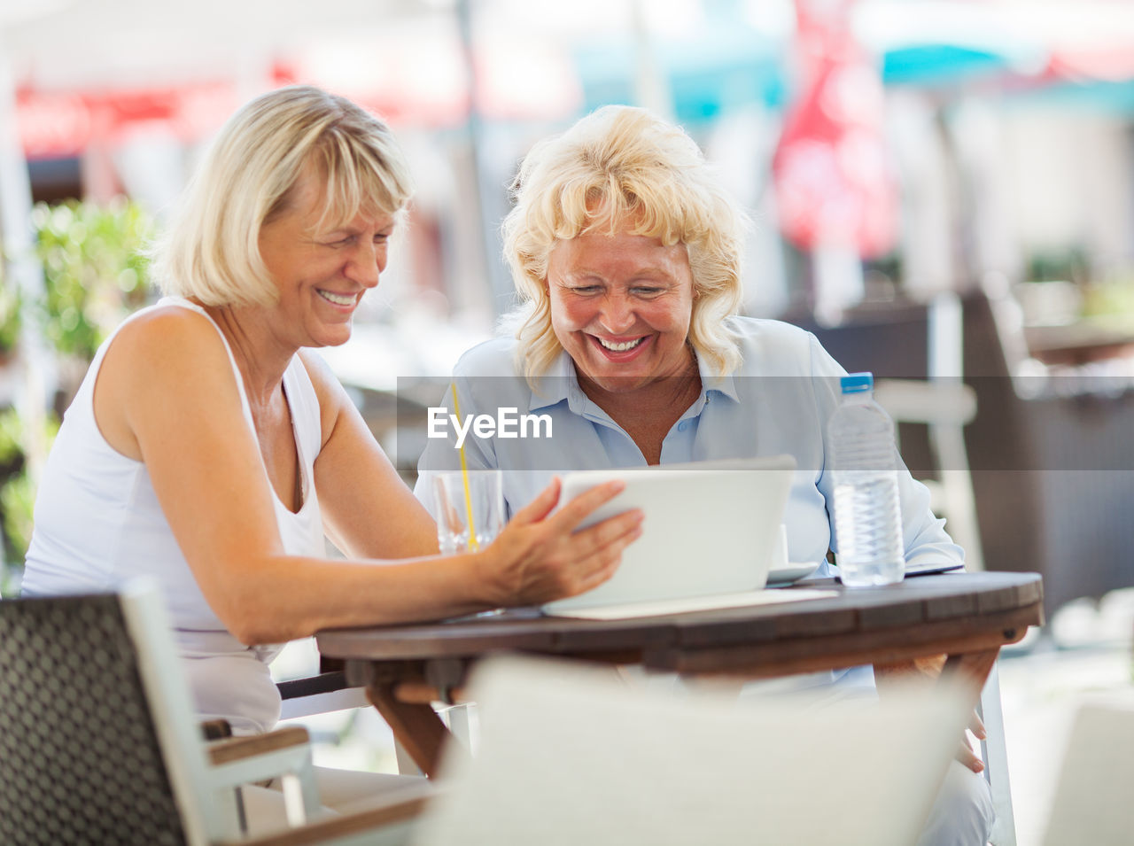 Smiling females using digital tablet at table in cafe