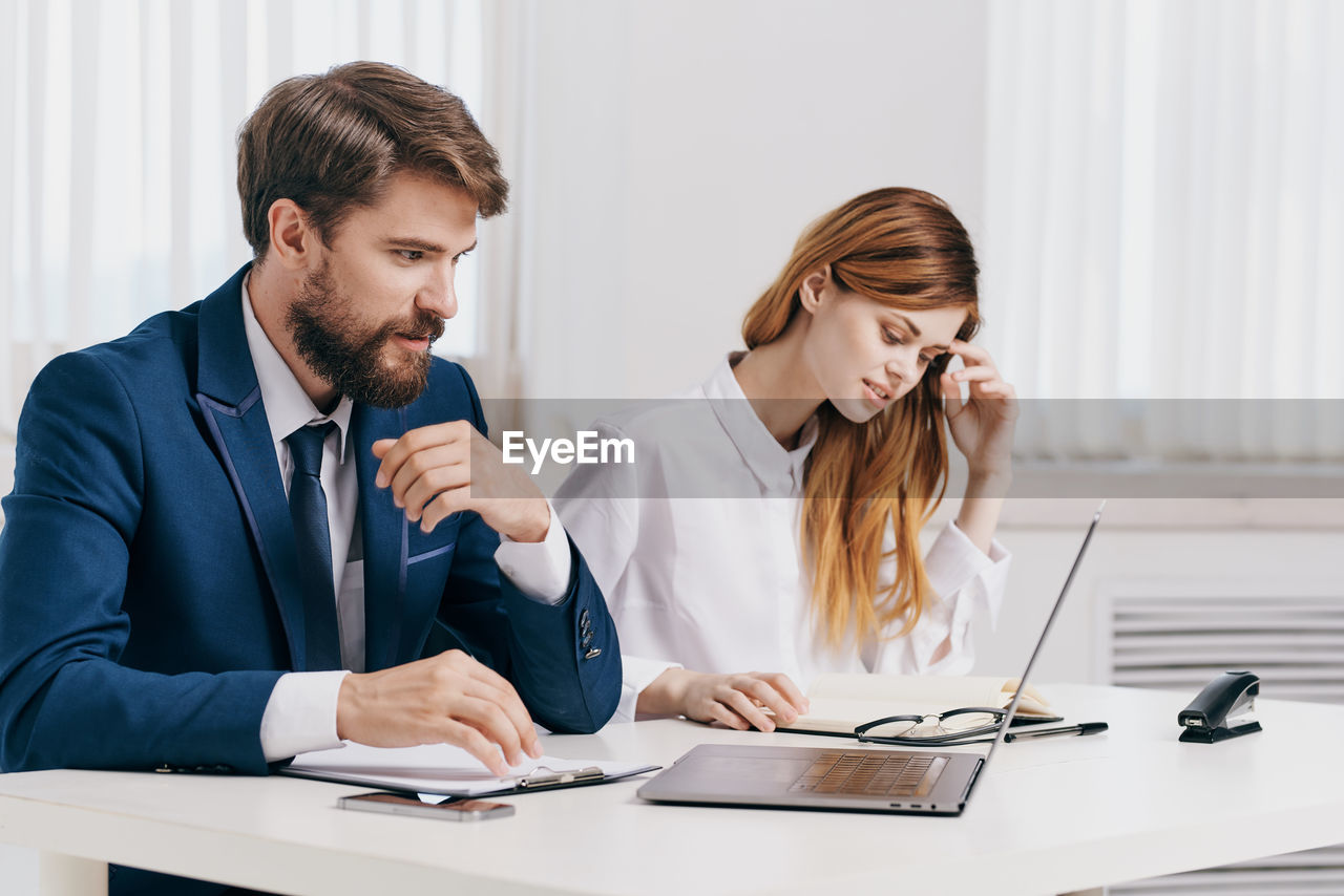 Business people using laptop while sitting at office