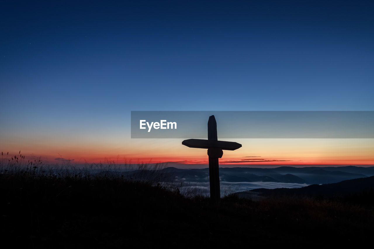 SILHOUETTE CROSS AGAINST ORANGE SKY