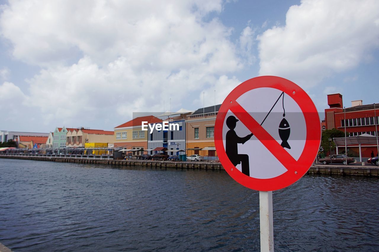 WARNING SIGN BY RIVER AGAINST SKY