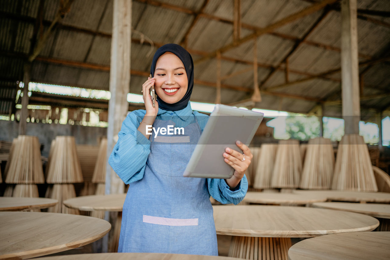 portrait of young woman using mobile phone while sitting on table