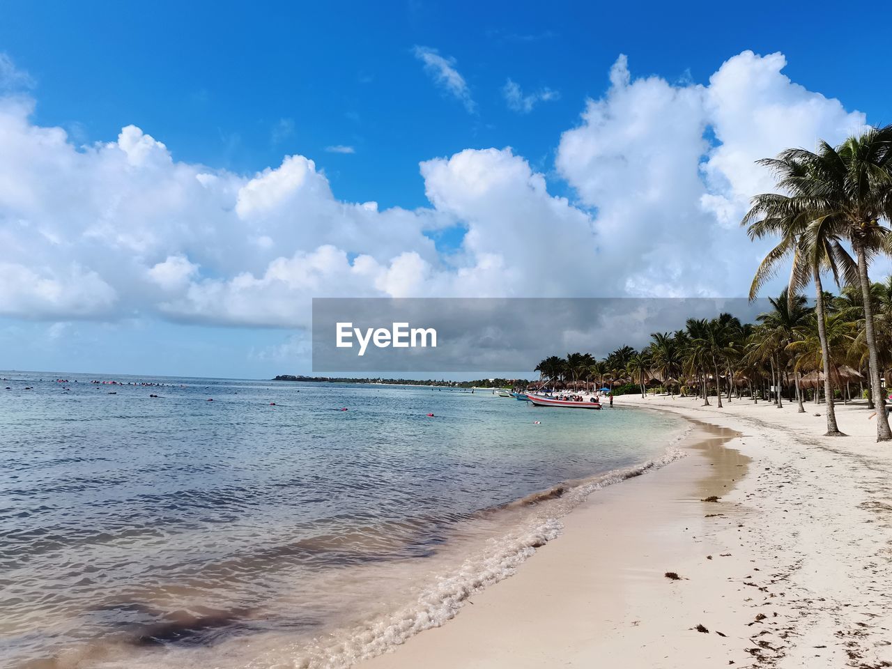land, beach, sea, water, sky, tropical climate, sand, palm tree, travel destinations, nature, scenics - nature, cloud, vacation, tree, trip, beauty in nature, body of water, travel, holiday, shore, island, environment, ocean, tranquility, tourism, blue, coconut palm tree, coastline, coast, plant, landscape, tropical tree, tranquil scene, water's edge, idyllic, summer, seascape, horizon over water, outdoors, relaxation, wave, tropics, tourist resort, horizon, day, sunlight, sunny, lagoon, no people, motion, sun, bay of water, coconut, arriving, urban skyline, bay, sports, non-urban scene, water sports, architecture