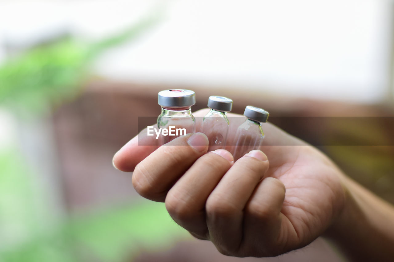 Cropped hand of person holding glass bottles