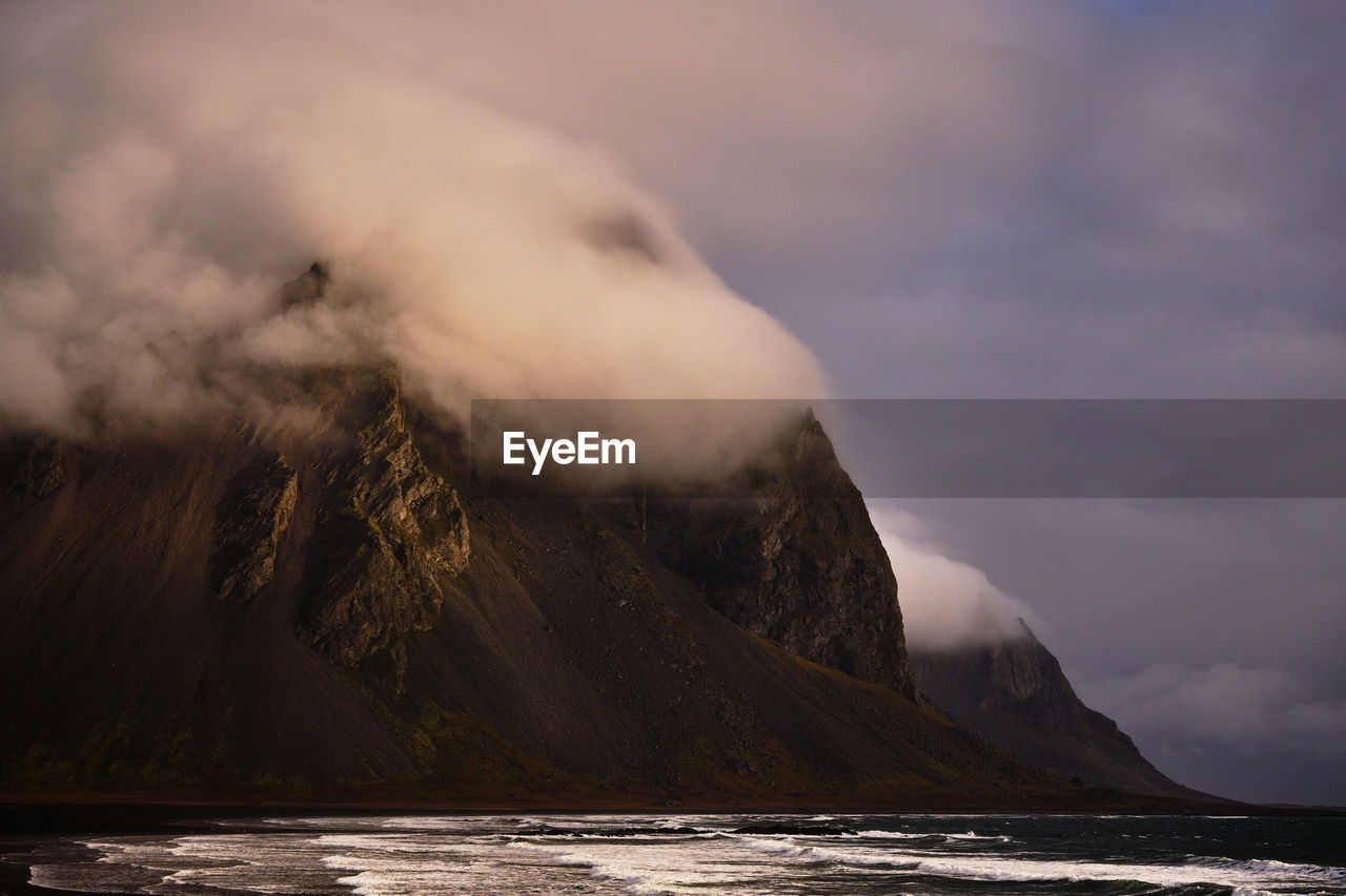 Scenic view of mountain by sea against sky