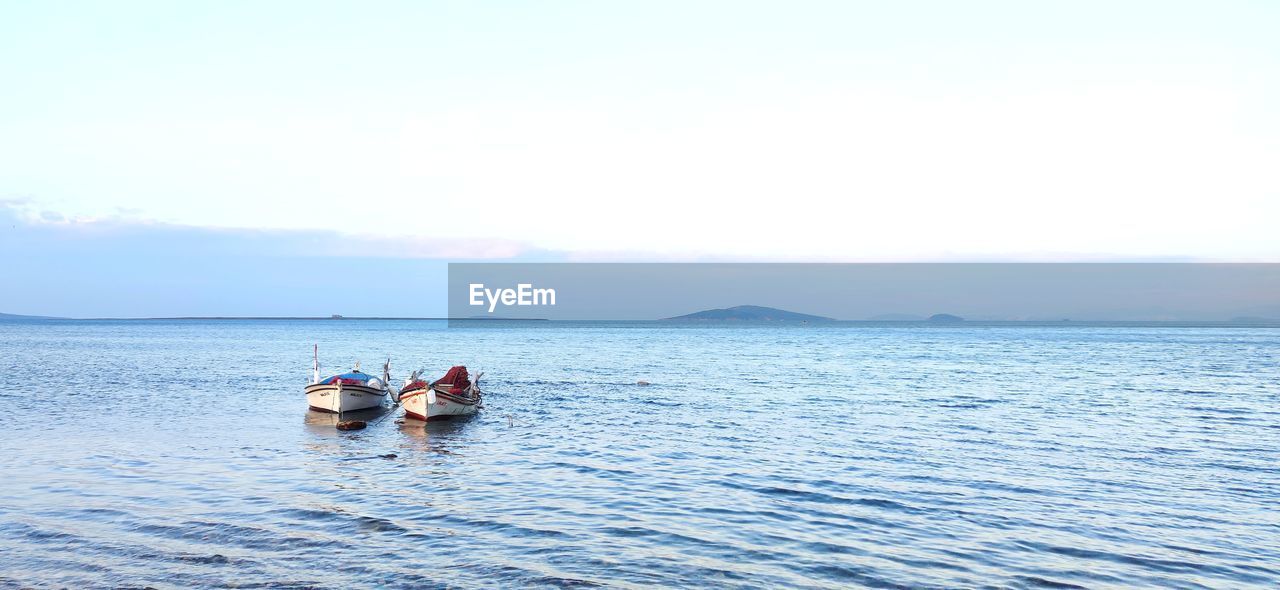 PEOPLE IN BOAT ON SEA AGAINST SKY