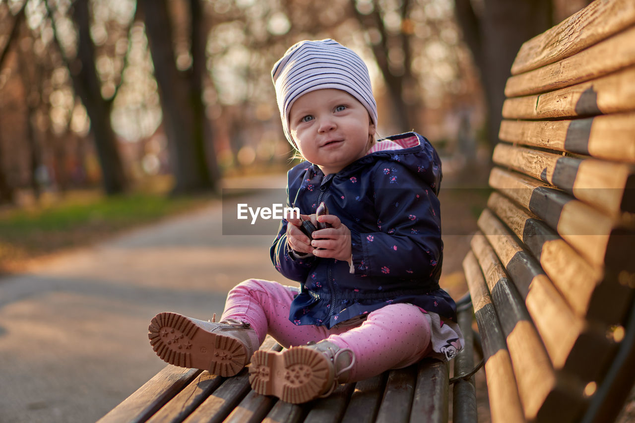 Full length of girl sitting on wood bench