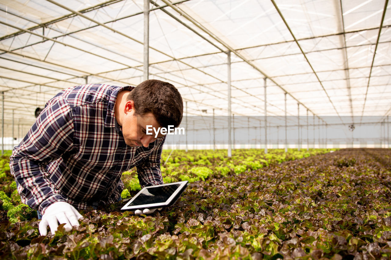 side view of young man using laptop while standing on field