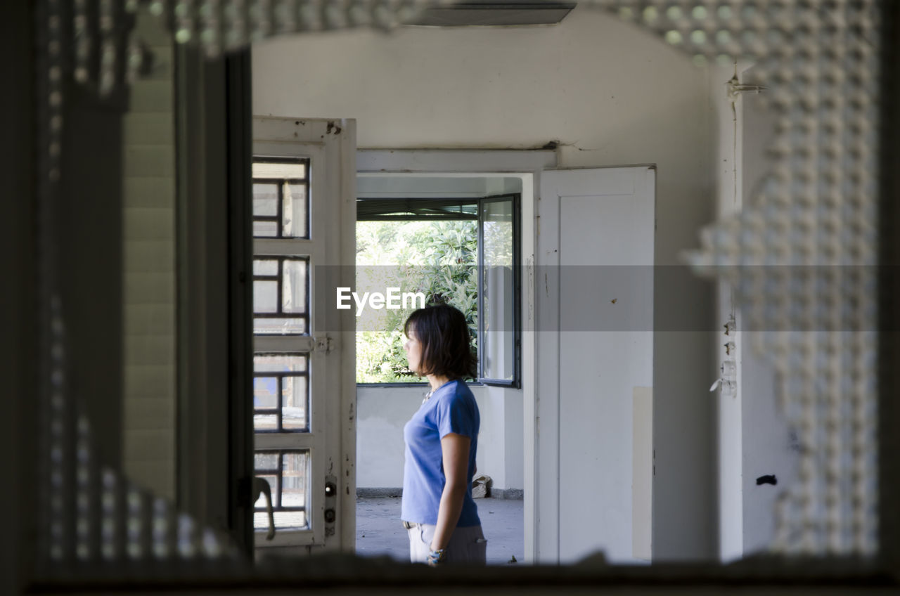 Side view of woman seen through broken window