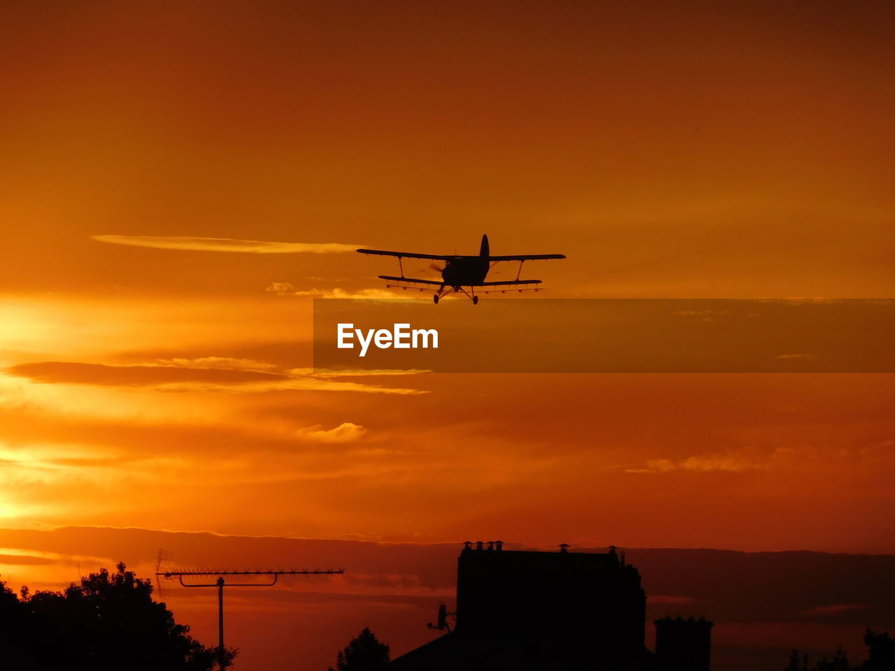 LOW ANGLE VIEW OF SILHOUETTE AIRPLANE FLYING AGAINST ORANGE SKY