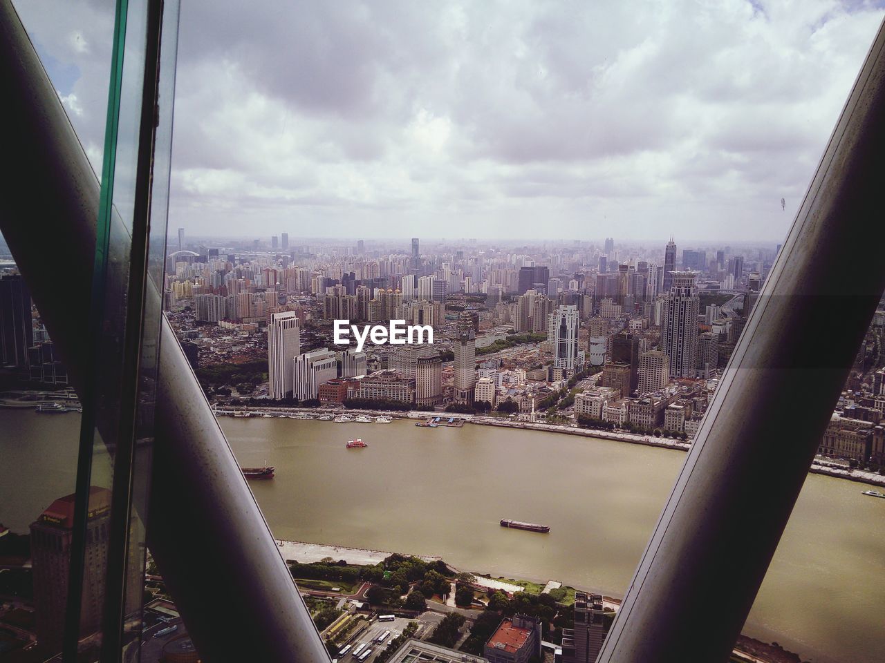 AERIAL VIEW OF CITY AGAINST SKY SEEN THROUGH GLASS WINDOW