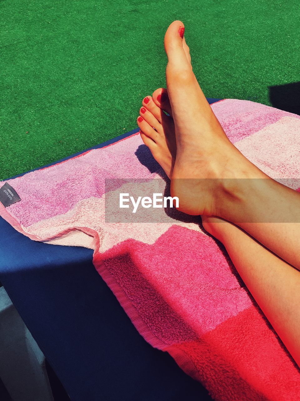 Low section of woman relaxing on lounge chair during sunny day