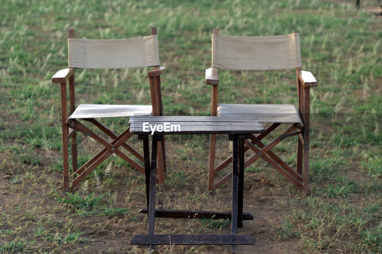 Empty foldable chairs and table on field