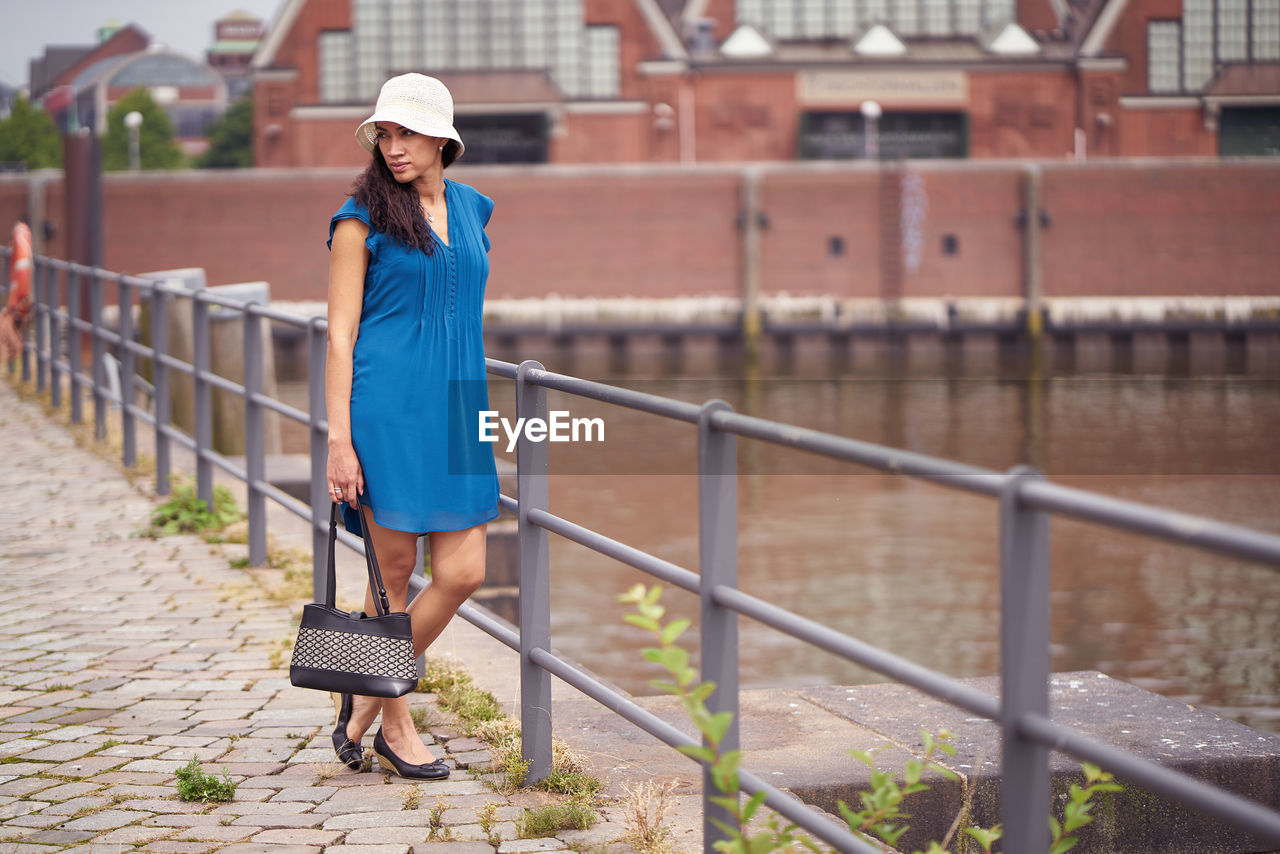 Mid adult woman standing on footpath by river