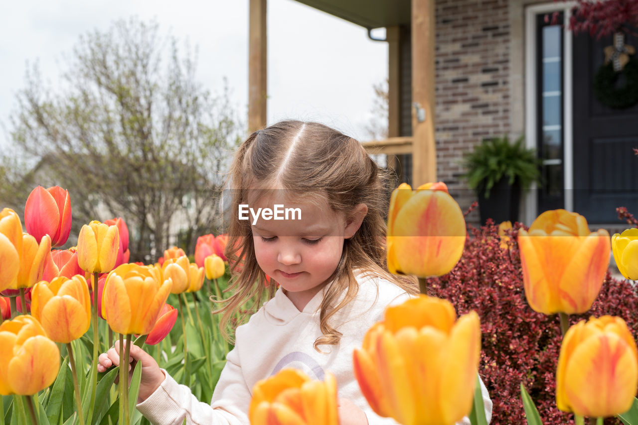 HIGH ANGLE VIEW OF GIRL HOLDING FLOWERING PLANTS AT HOME