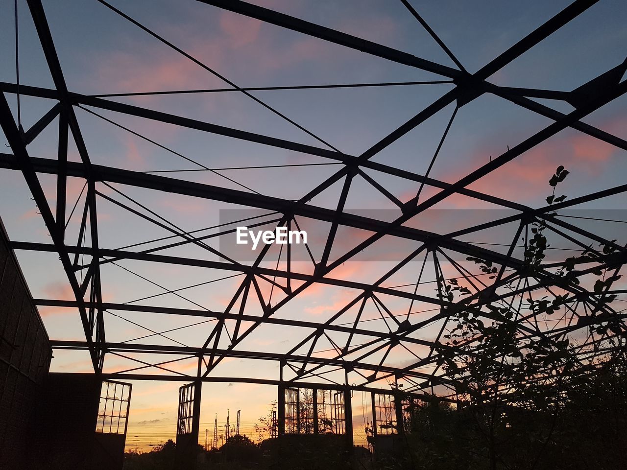 Low angle view of silhouette metallic built structure against sky during sunset