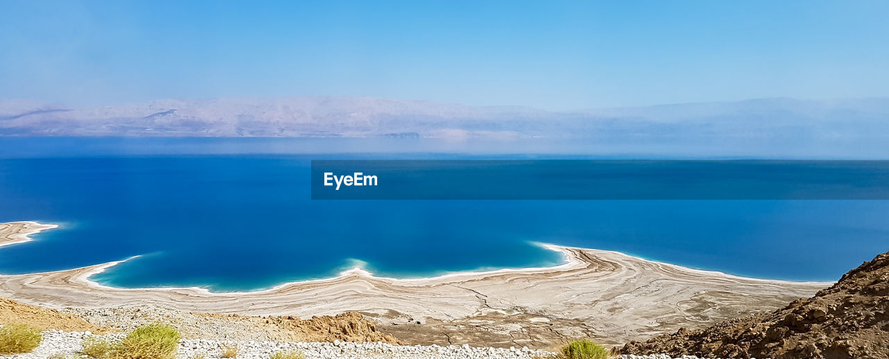 Panoramic view of sea and mountains against blue sky