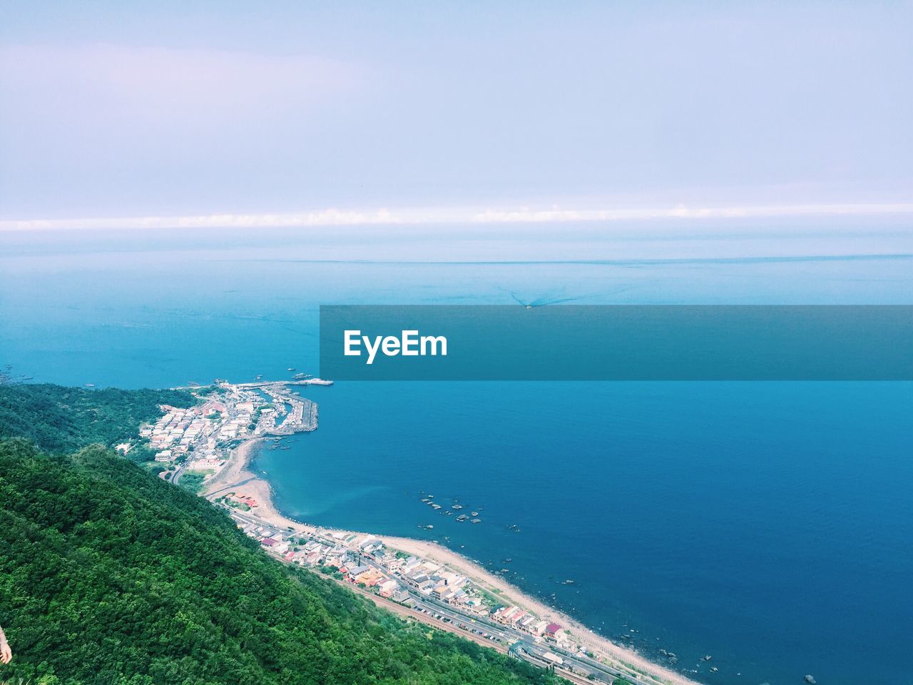 Aerial view of sea with human settlement and trees against sky