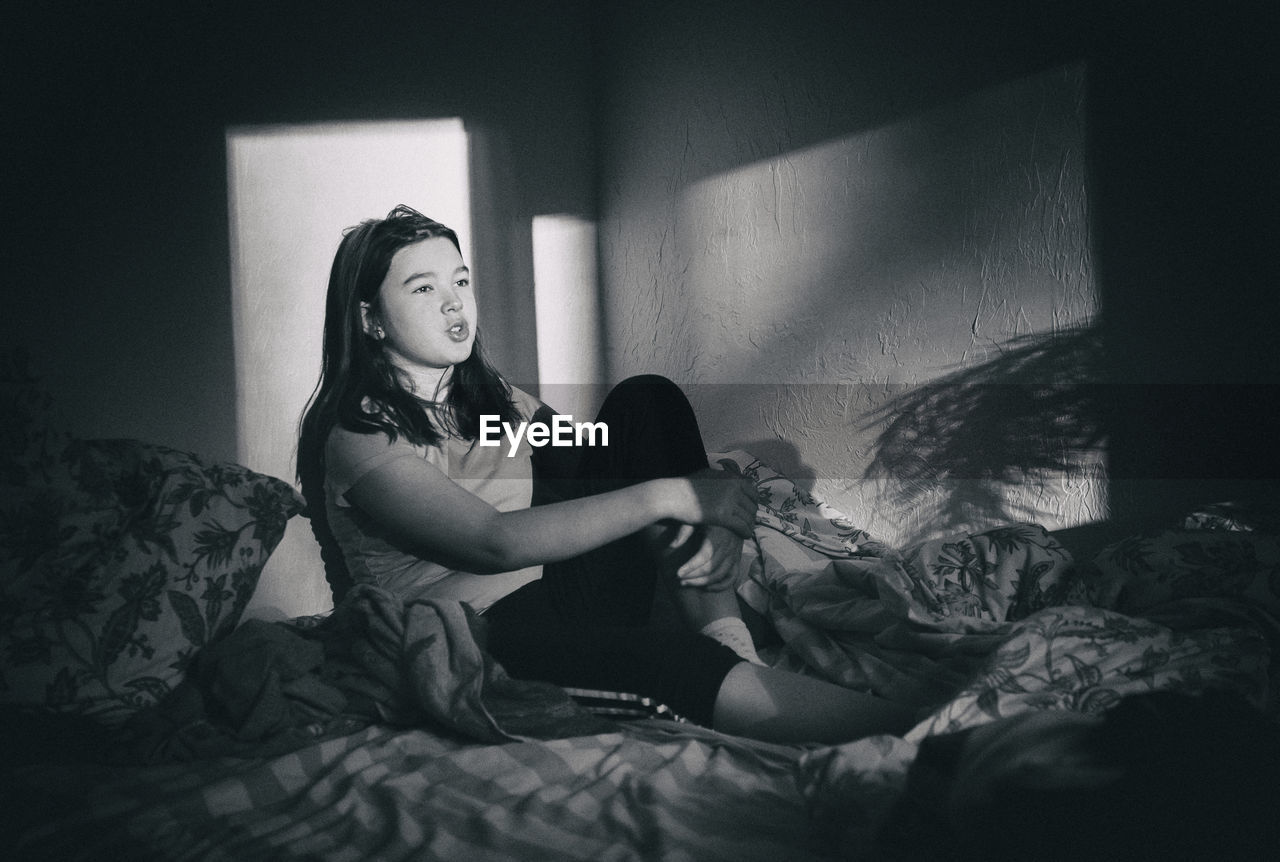 Thoughtful teenage girl relaxing on bed