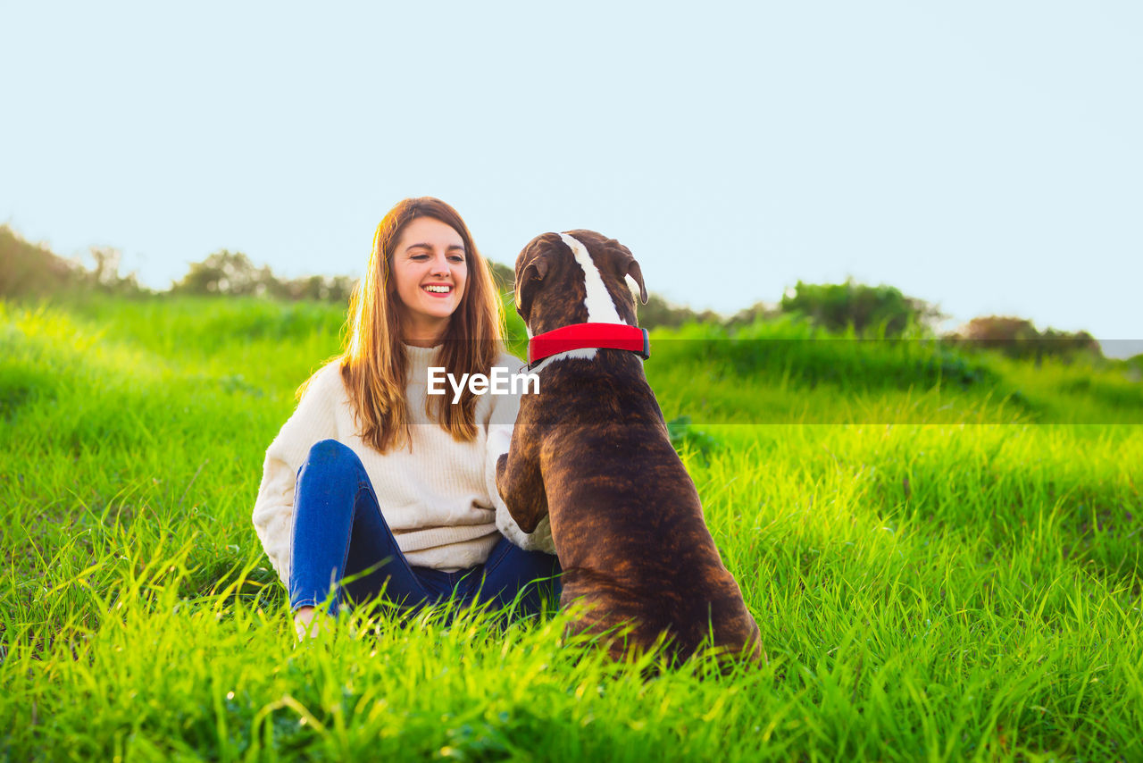 Portrait of woman with dog sitting on field