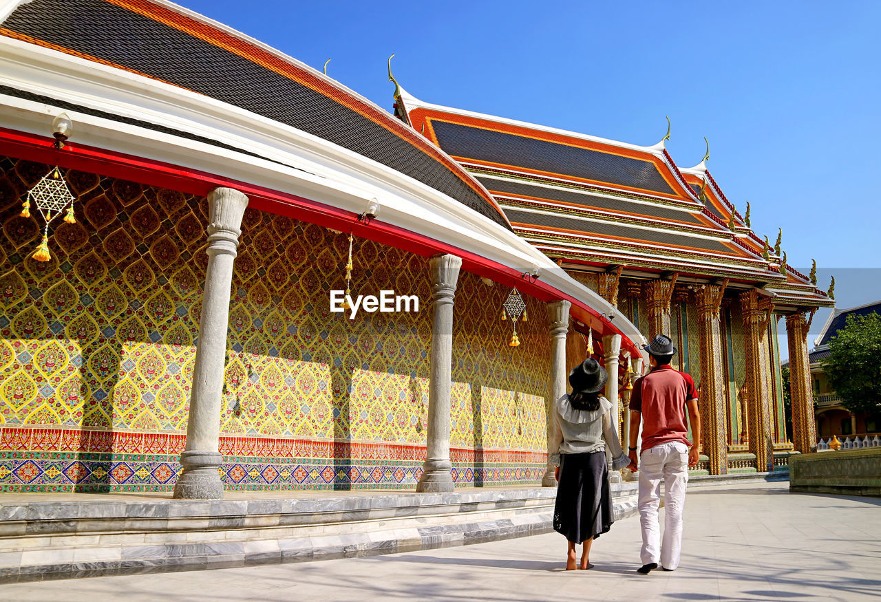 Couple walking along the circular gallery of wat ratchabophit buddhist temple, bangkok, thailand