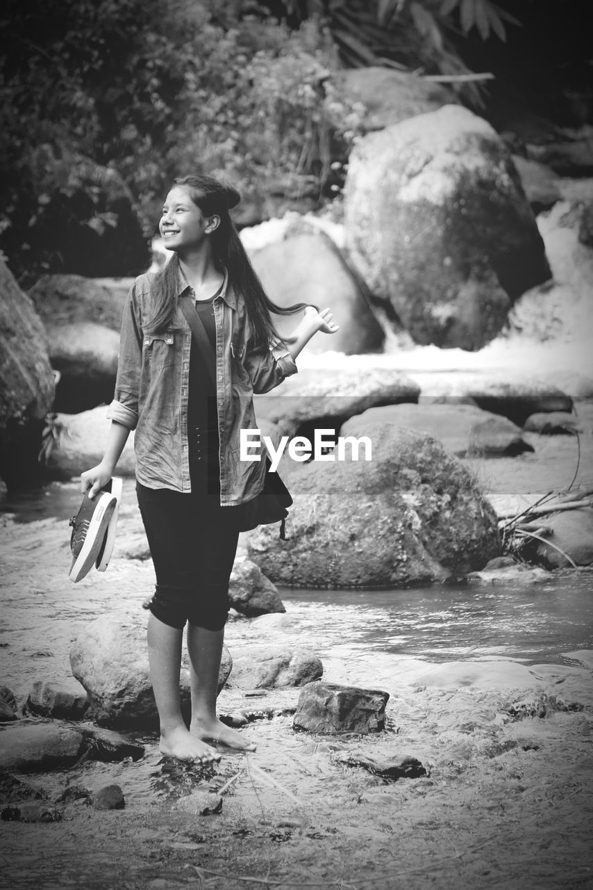 Young woman standing on rock at river