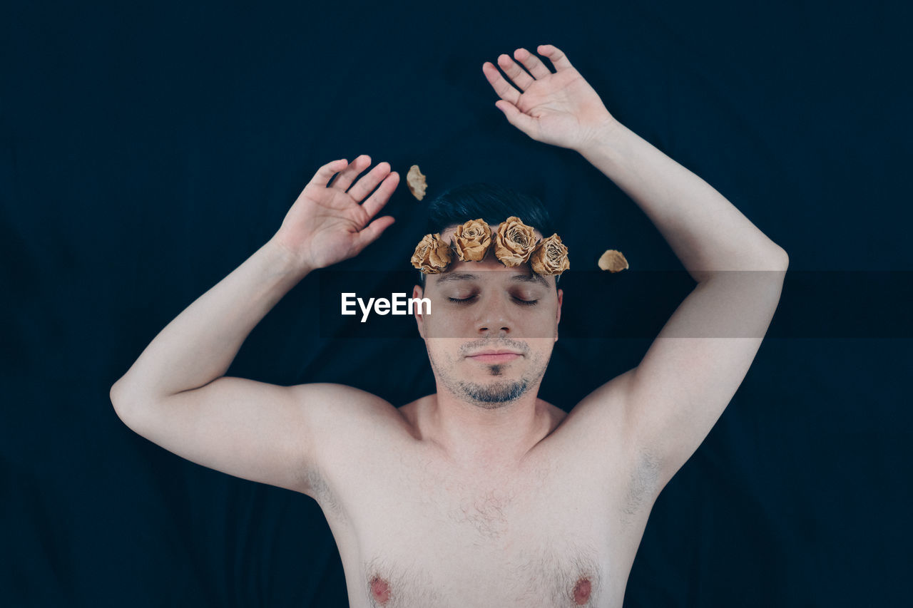 Man wearing flowers sleeping on bed