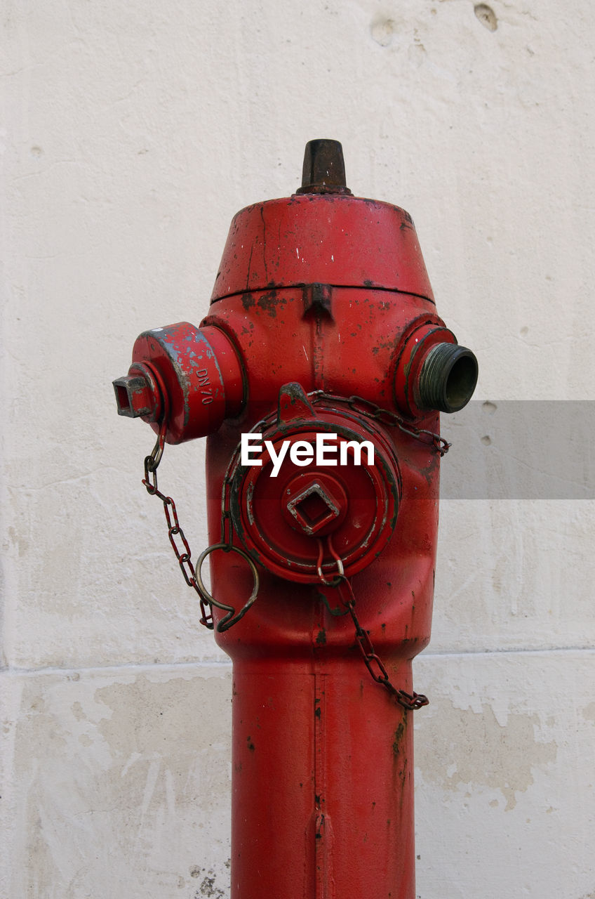 Close-up of red fire hydrant against wall