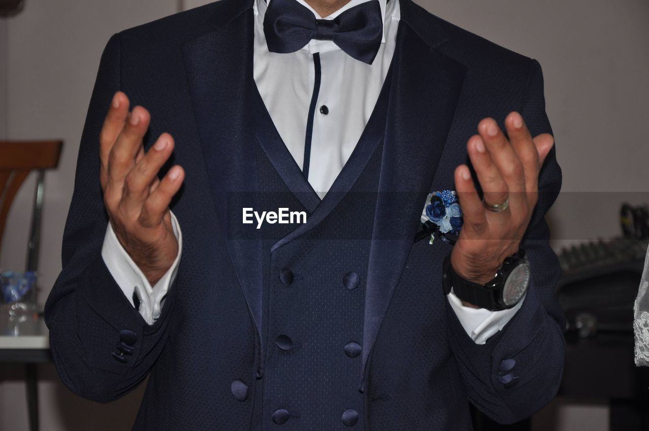 formal wear, tuxedo, one person, adult, bow tie, men, clothing, indoors, collar, blazer, fashion, front view, standing, arts culture and entertainment, business, midsection, person, elegance, ring, coat