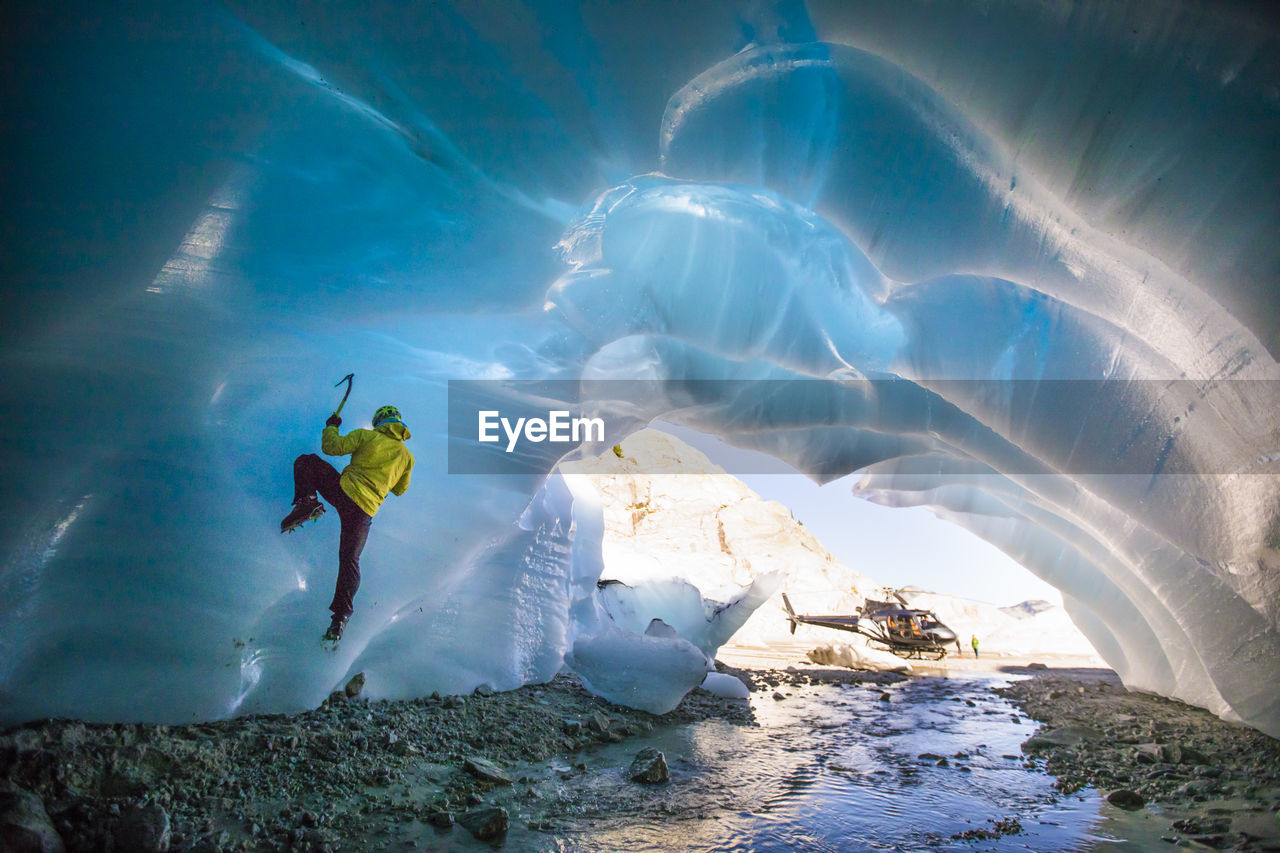 Man ice climbing in ice cave during luxury adventure tour.