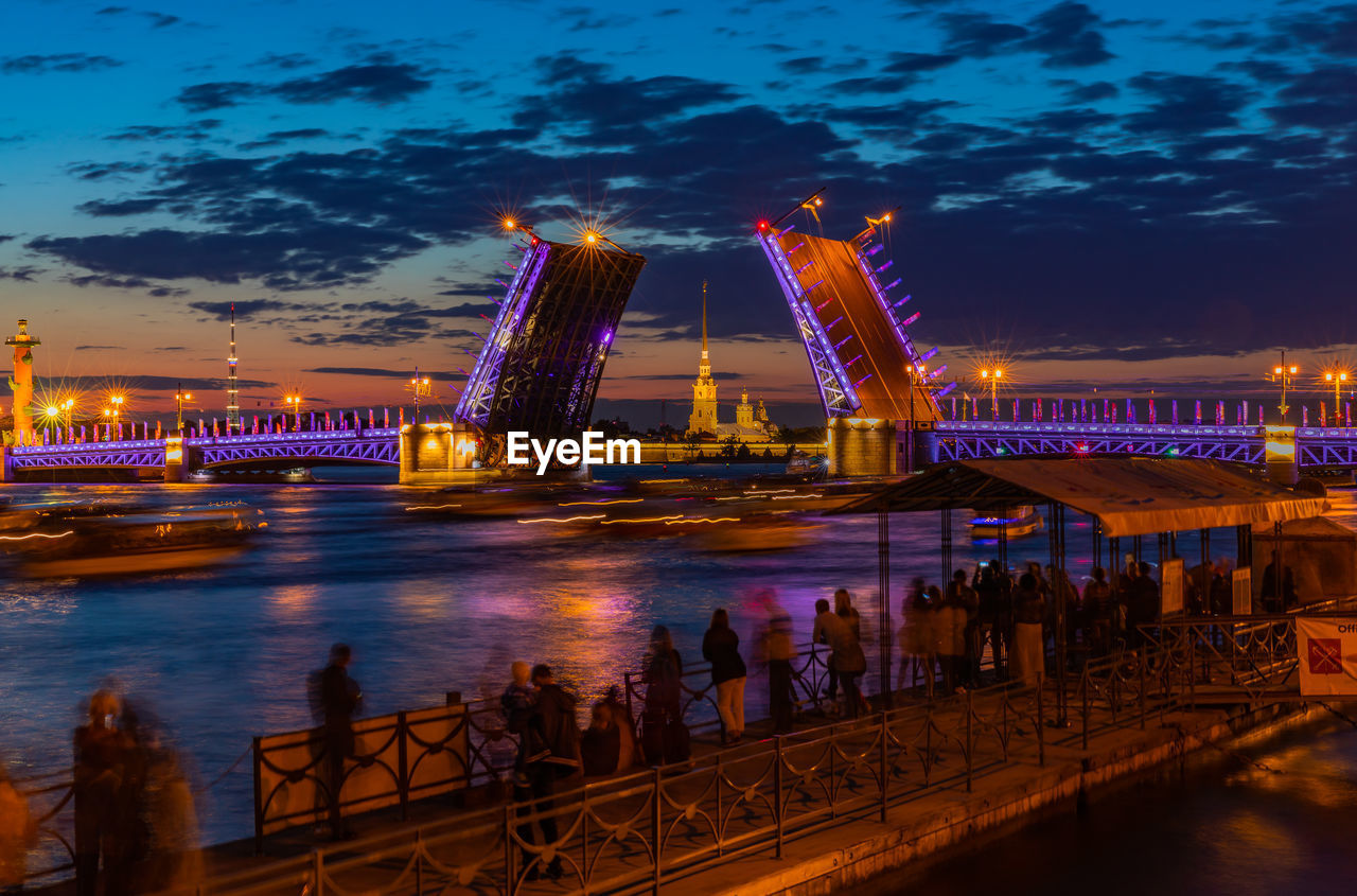 Illuminated bridge over river against sky at night