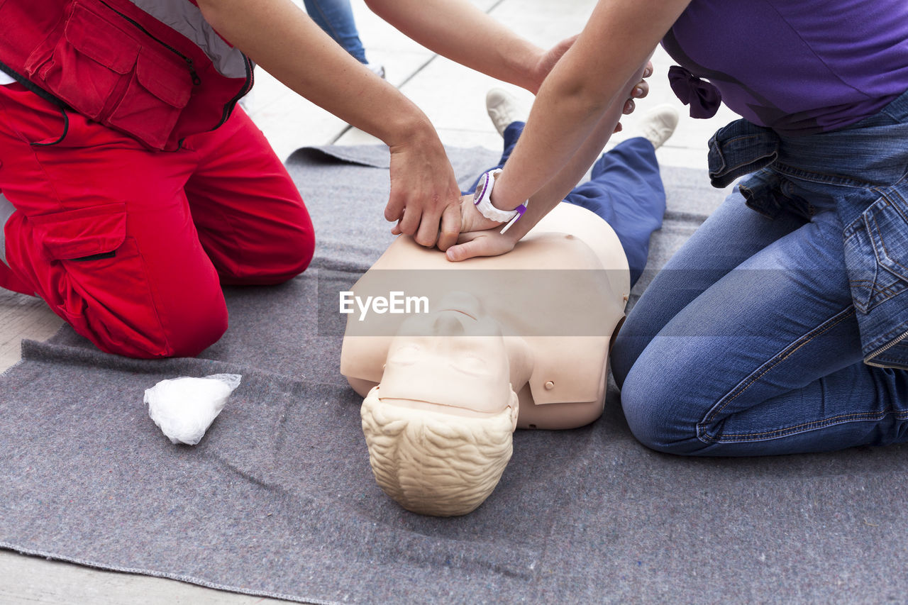 Midsection of people pressing figurine chest outdoors