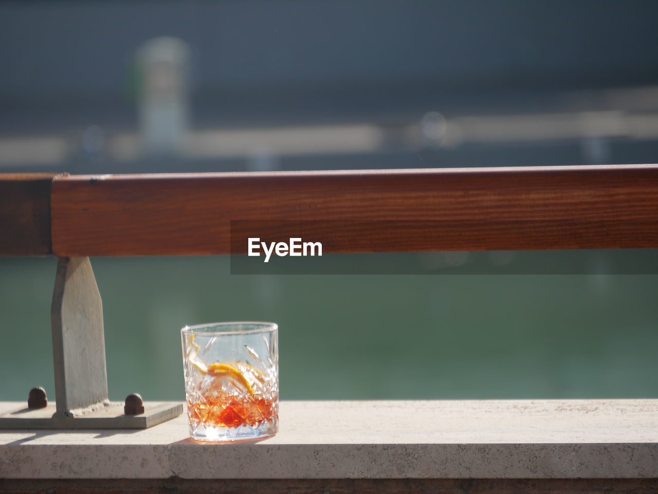 CLOSE-UP OF GLASS ON TABLE AGAINST BLURRED BACKGROUND