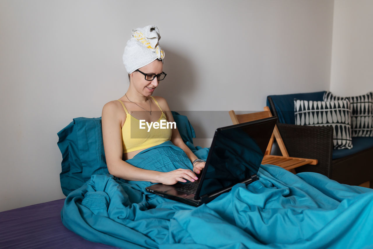 Portrait of young woman sitting on bed at home