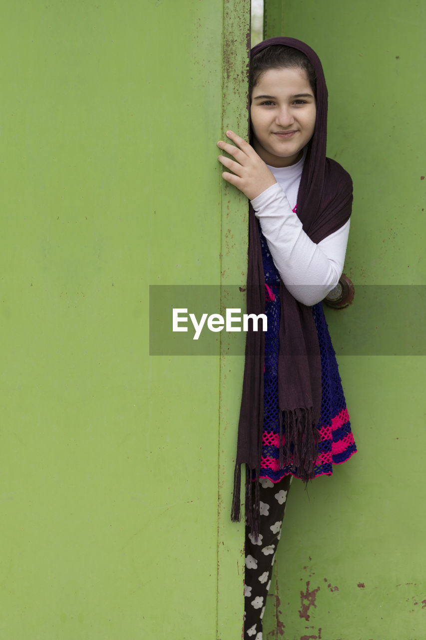 Portrait of girl standing by green door