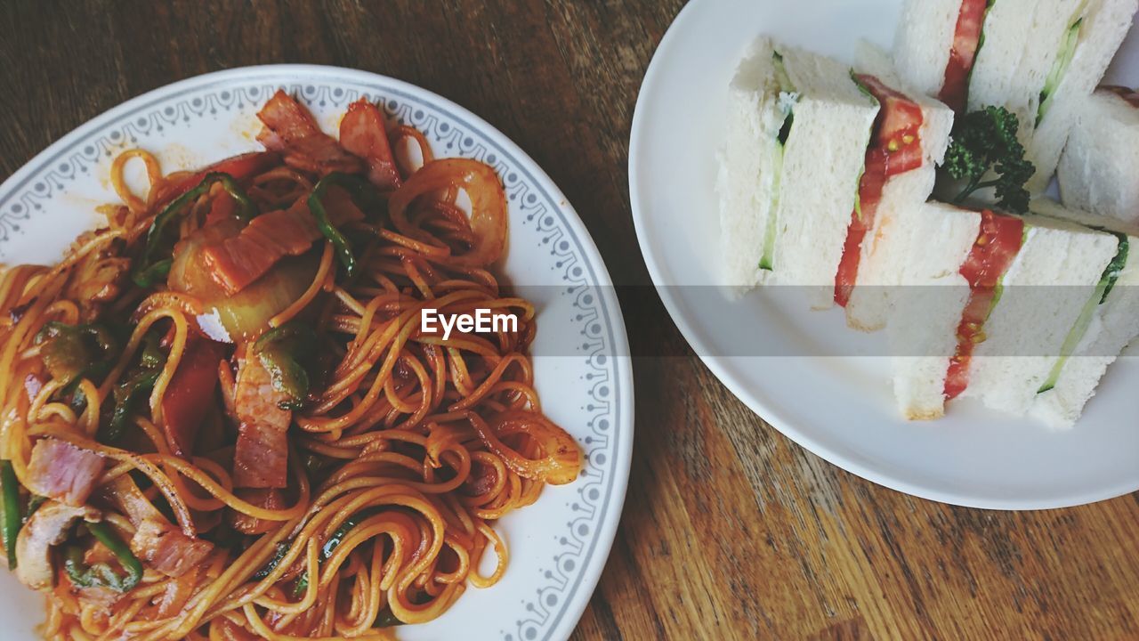 Directly above shot of sandwiches and noodles in plates on table